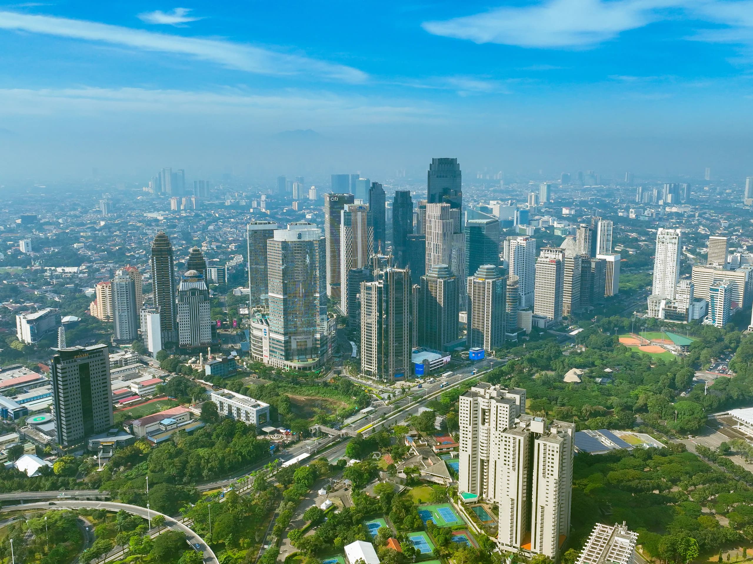 Capturing Jakarta’s panoramic skyline from an aerial perspective, this visual showcases towering skyscrapers, modern business districts, and expansive green spaces that define the dynamic character of Indonesia’s capital. Through aerial cinematography, the city reveals its architectural beauty, impressive urban landscape, and the harmonious contrast between modern development and nature.