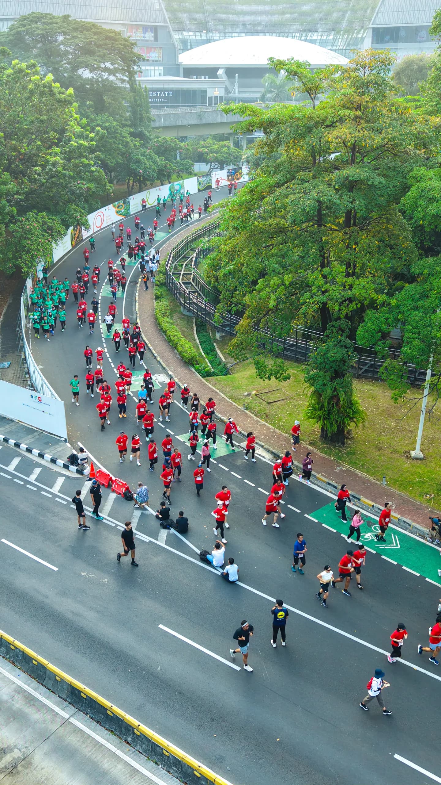 Capturing the energy and excitement of Alfamart Event 2026, this aerial perspective showcases participants running along a vibrant city route surrounded by lush greenery and modern urban architecture. The visual highlights the event’s dynamic atmosphere, community spirit, and memorable moments through professional event documentation.